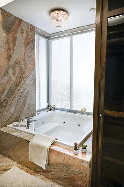 Luxurious bathroom interior design with a marble jacuzzi tub, elegant chandelier, and large frosted window.