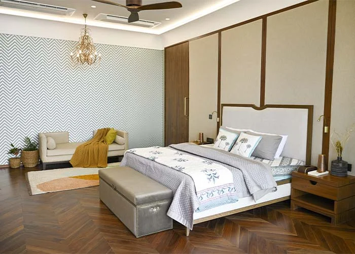 DESIGN CHRONICLES Contemporary bedroom interior with modern decor, featuring a stylish queen-sized bed with patterned linens, elegant wooden side tables, and a cozy seating area accented by a mustard throw
