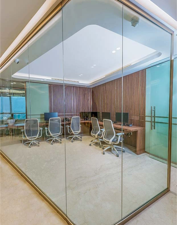 A modern glass office featuring a sleek desk and comfortable chairs, a Luxury Interior Designer designed for a professional workspace.