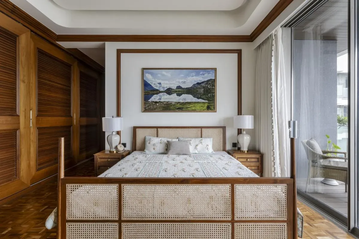 Bedroom at The Colonial Home by 7Nirvana, with a cane-detailed bed, teak louvred wardrobes and a landscape photograph