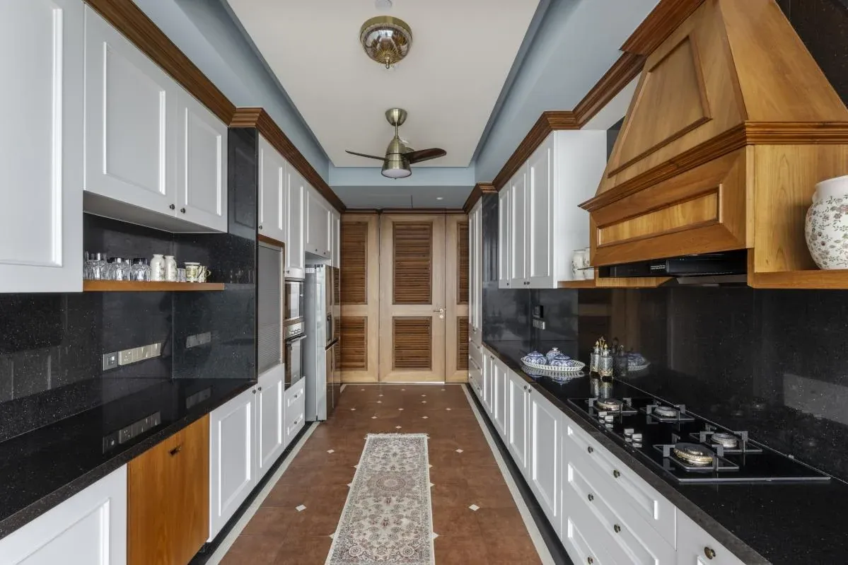 Kitchen at The Colonial Home by 7Nirvana, with white shutters, black granite, classical moulded woodwork and a terracotta floor